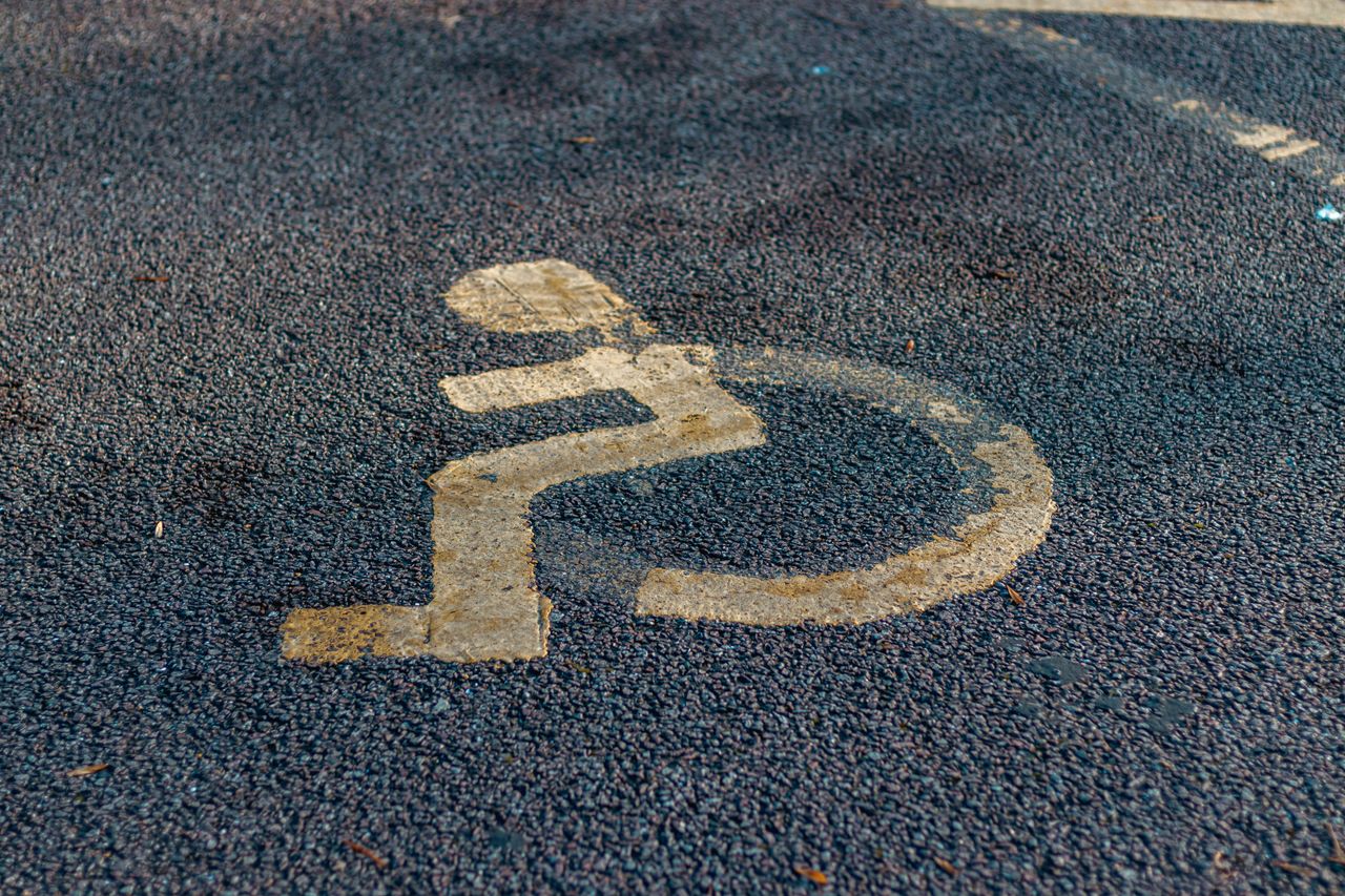 Close-up of a weathered handicap sign painted on a pavement, emphasizing accessibility.