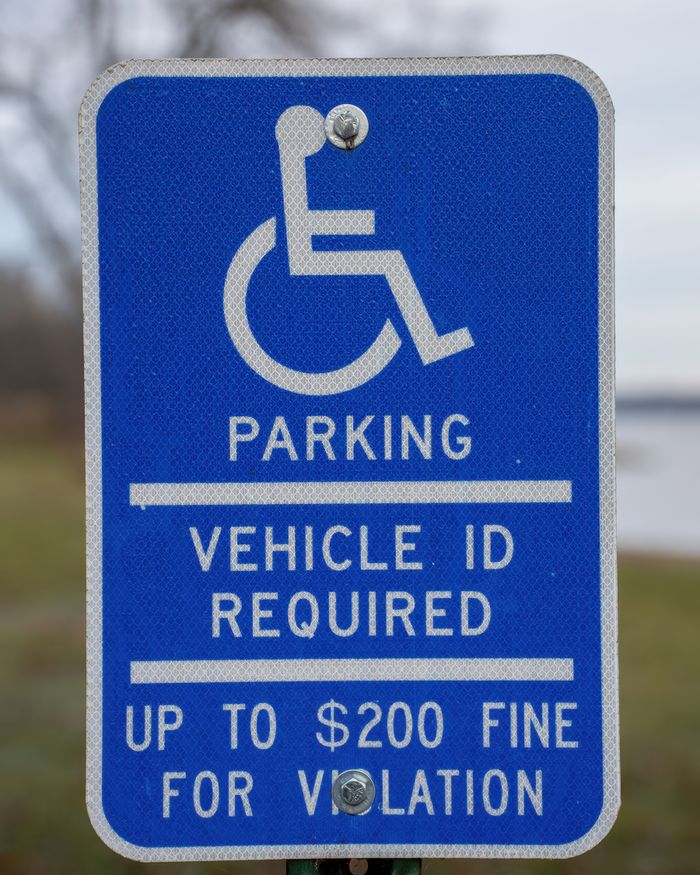 Service Blue handicap parking sign indicating vehicle ID requirement and fine.