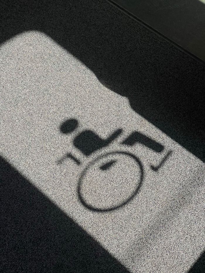 Service Shadow of a wheelchair symbol projected on a textured floor, indicating accessibility.